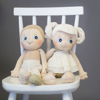 The Rubens EcoBuds dolls Aspen and Hazel sitting on a white chair