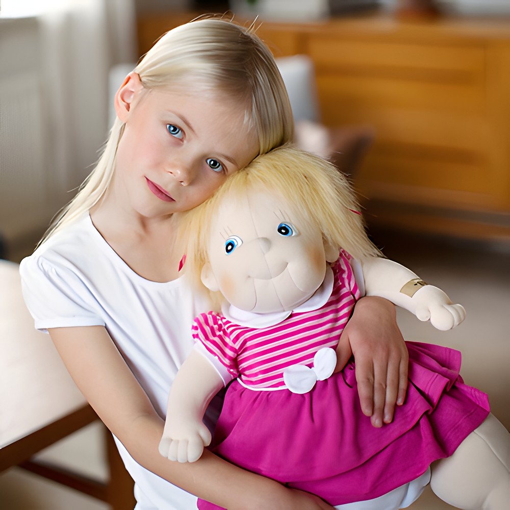 Kind umarmt die Rubens Barn Original-Puppe Ida mit blondem Haar