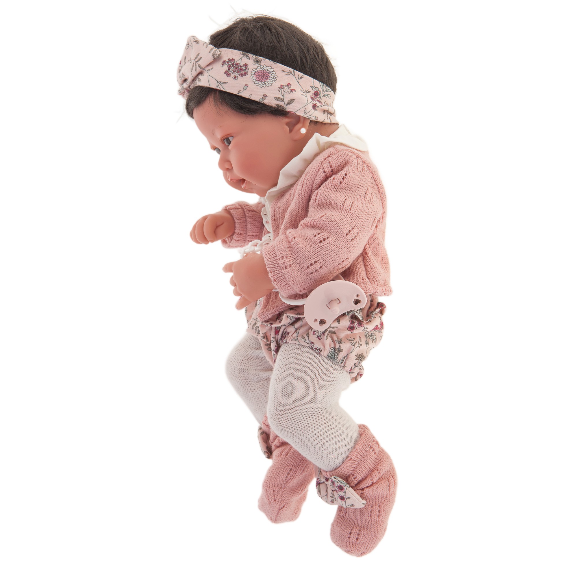 Antonio Juan baby doll Pipa, realistic doll with dark hair in a pink knit outfit, side view with floral headband
