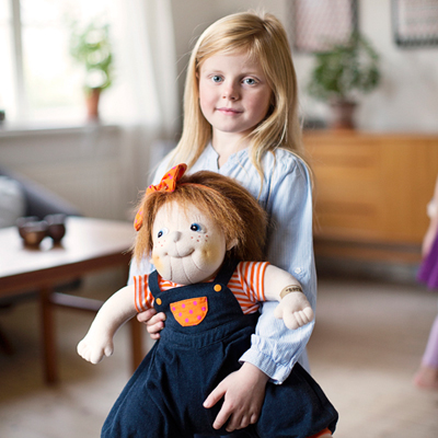 Kind hält die Rubens Barn Original-Puppe Anna im Wohnzimmer