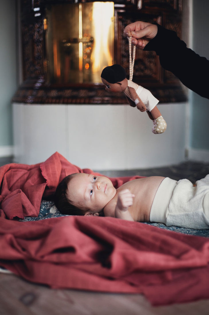 Die Rubens EcoBuds Mini-Puppe Basil wird einem liegenden Baby gereicht
