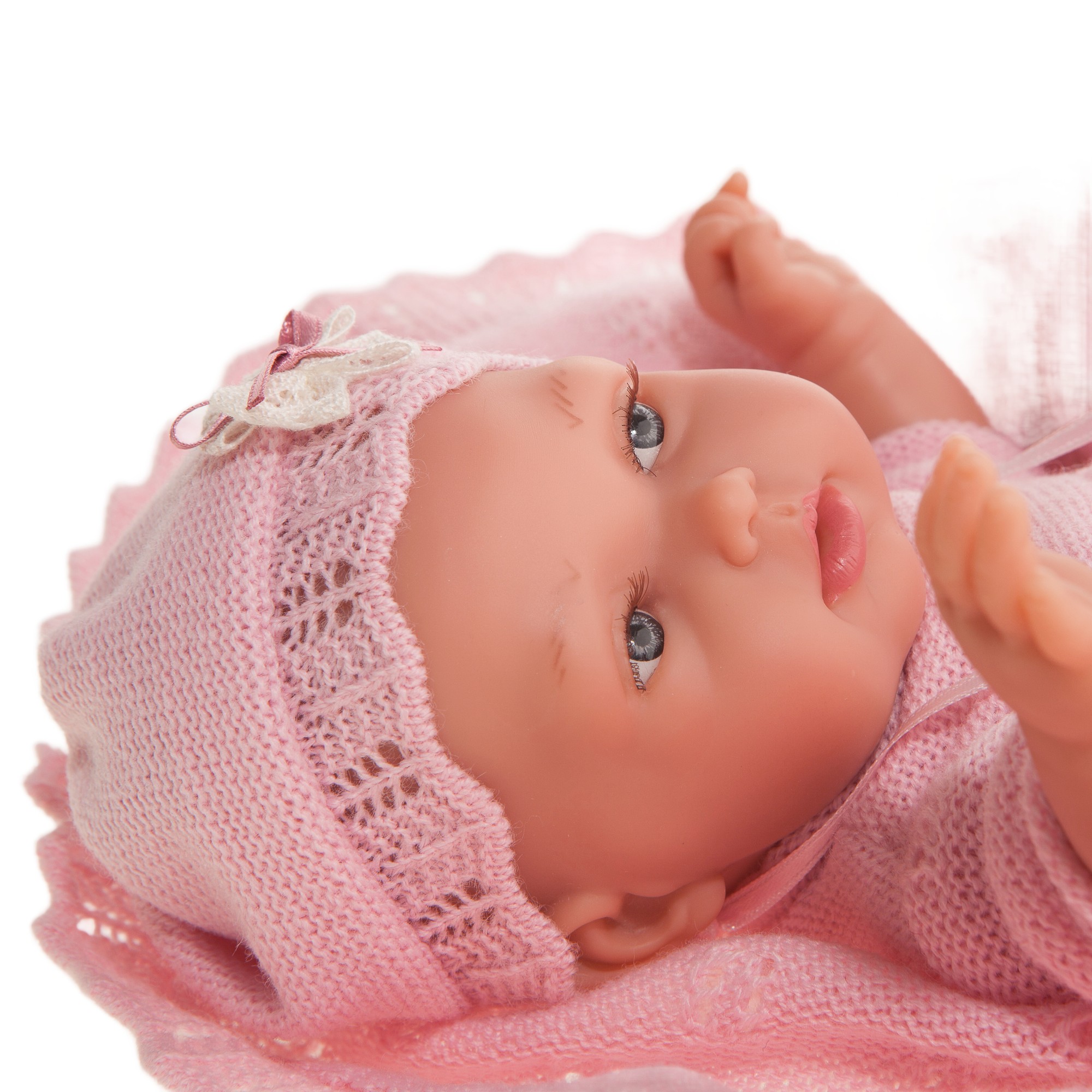 Antonio Juan baby doll Peke, close-up of the doll lying down with pink bonnet, hand close to the mouth