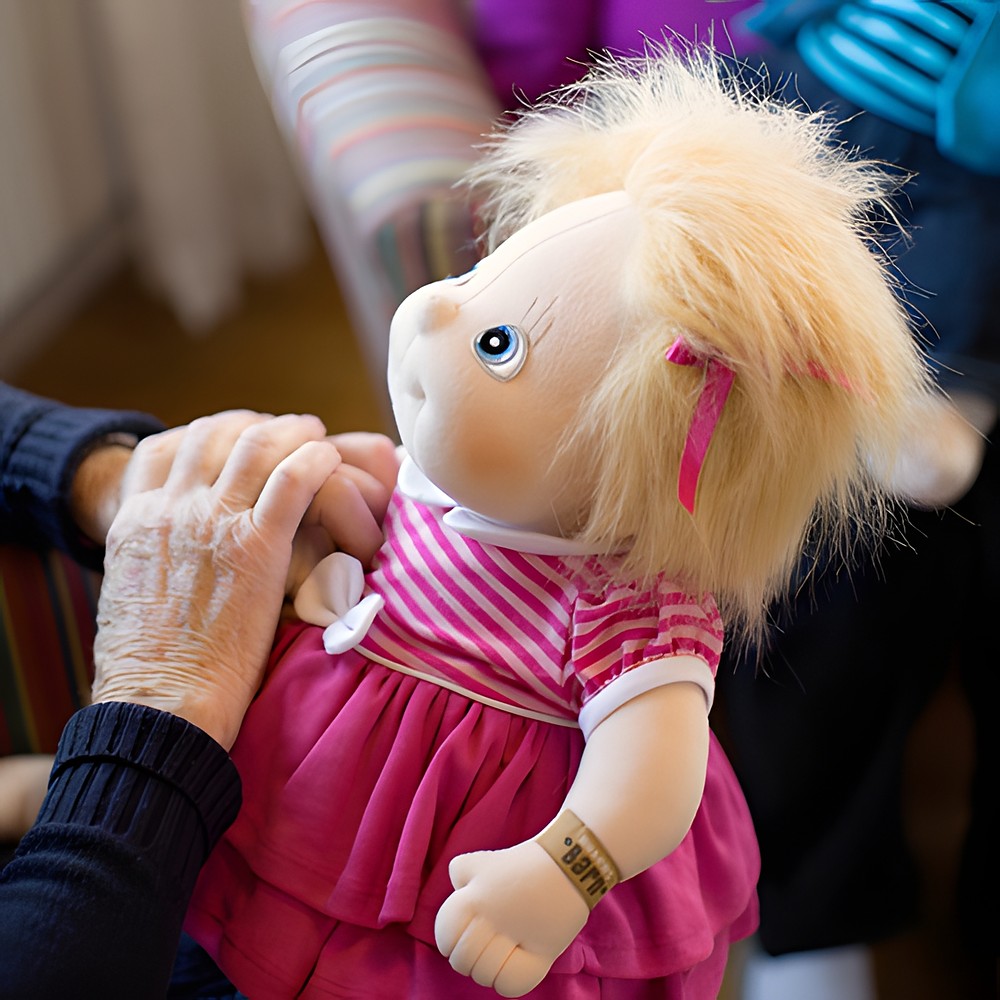 Seniorin berührt die Rubens Barn Original-Puppe Ida im pinken Kleid