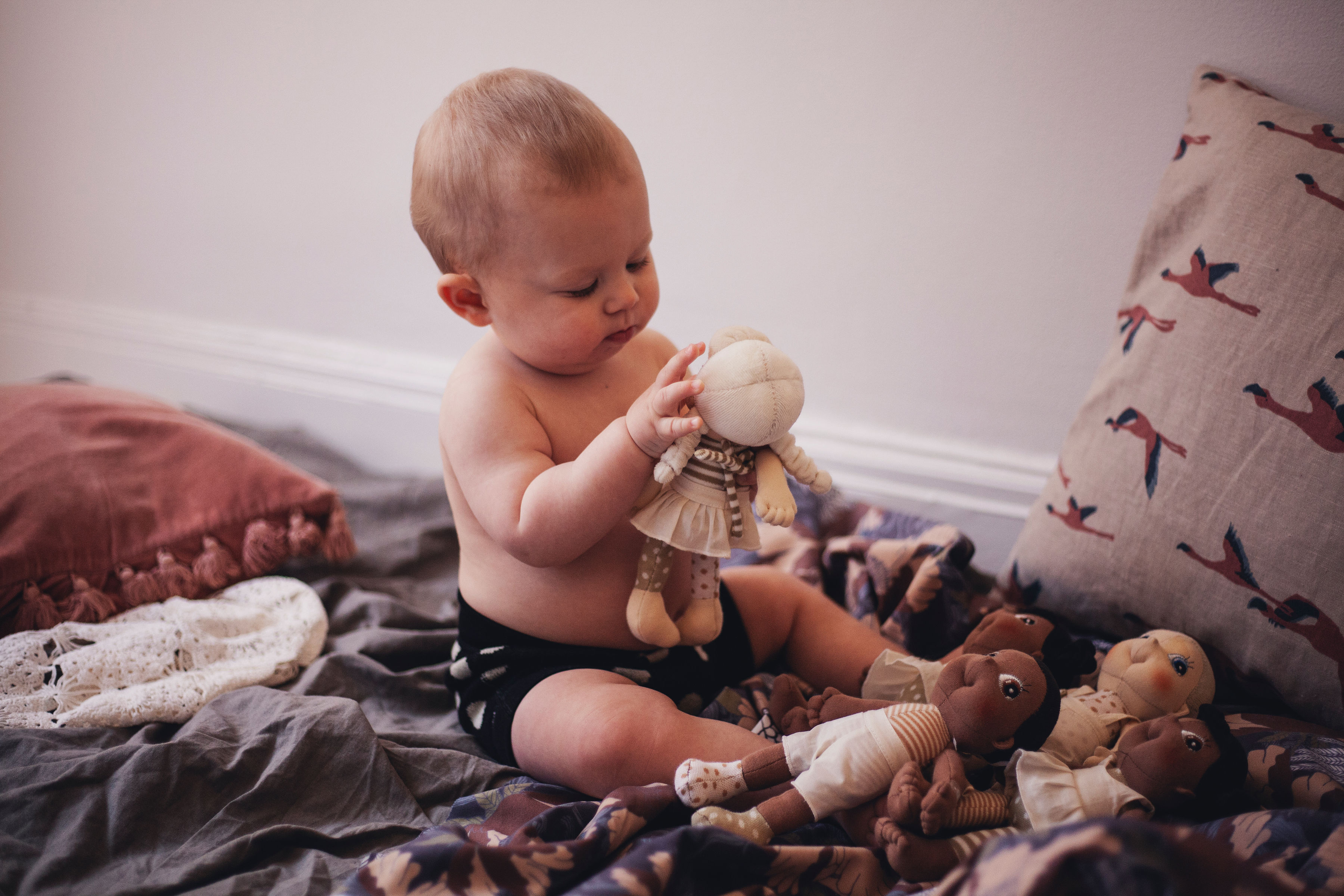 Baby spielt mit einer Rubens EcoBuds Mini-Puppe auf einer Decke