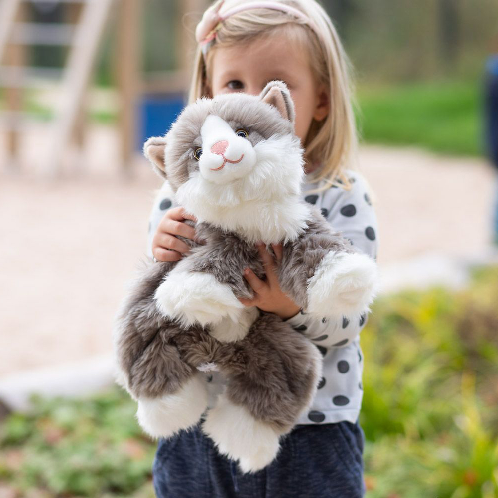 Child hugging the Joyk empathy doll Billy, a grey-white cat with fluffy fur