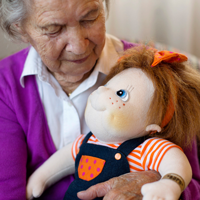 Seniorin hält die Rubens Barn Original-Puppe Anna im Arm