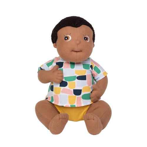 Rubens Barn baby doll Ali with dark hair, colourful patterned shirt and yellow nappy pants, sitting
