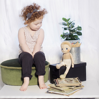 Child looking over at the Rubens EcoBuds doll on the wooden box