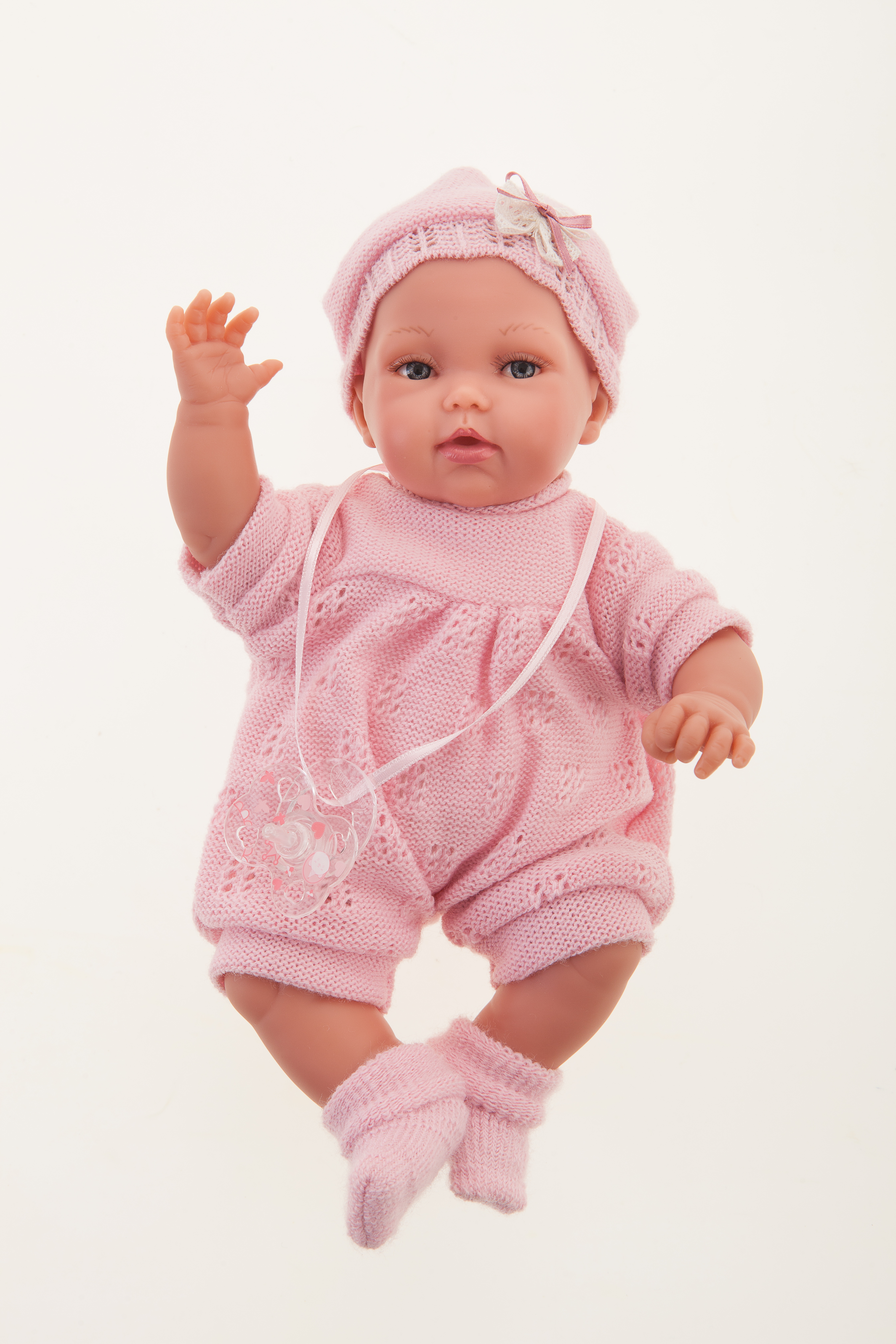 Antonio Juan baby doll Peke, realistic doll in a pink knit outfit with crocheted bonnet and bow, one arm raised, front view