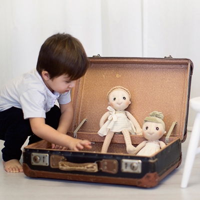 Child putting the Rubens EcoBuds dolls into an old suitcase