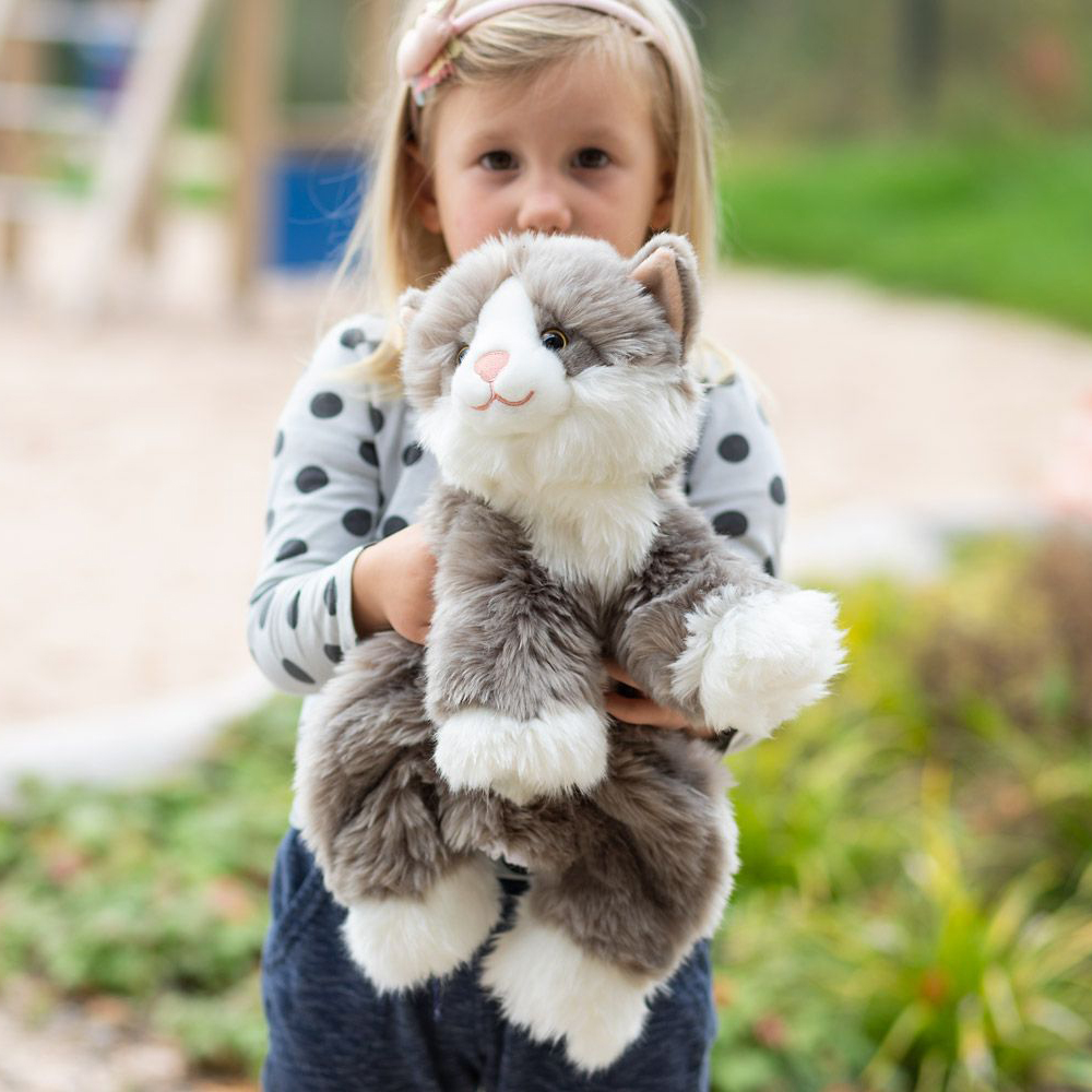 Child carrying the grey-white Joyk empathy doll Billy on the playground