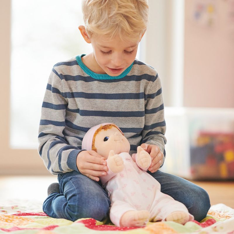 Junge hält die Joyk-Empathiepuppe Baby Emma