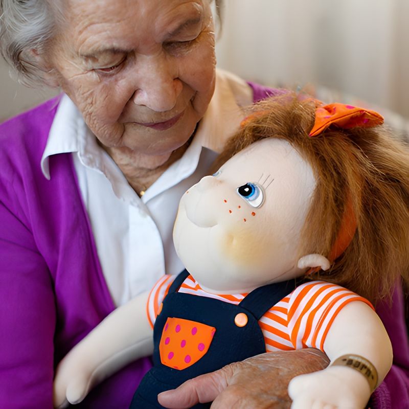 Seniorin hält die Rubens-Barn-Puppe Anna im Arm